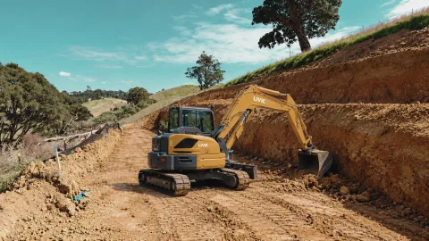 Livic excavator in sunlit earthworks.